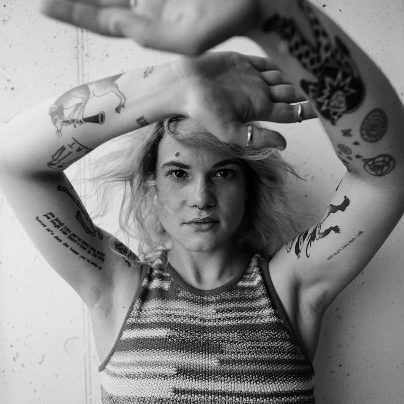 Black-and-white AVEC portrait with tattooed arms